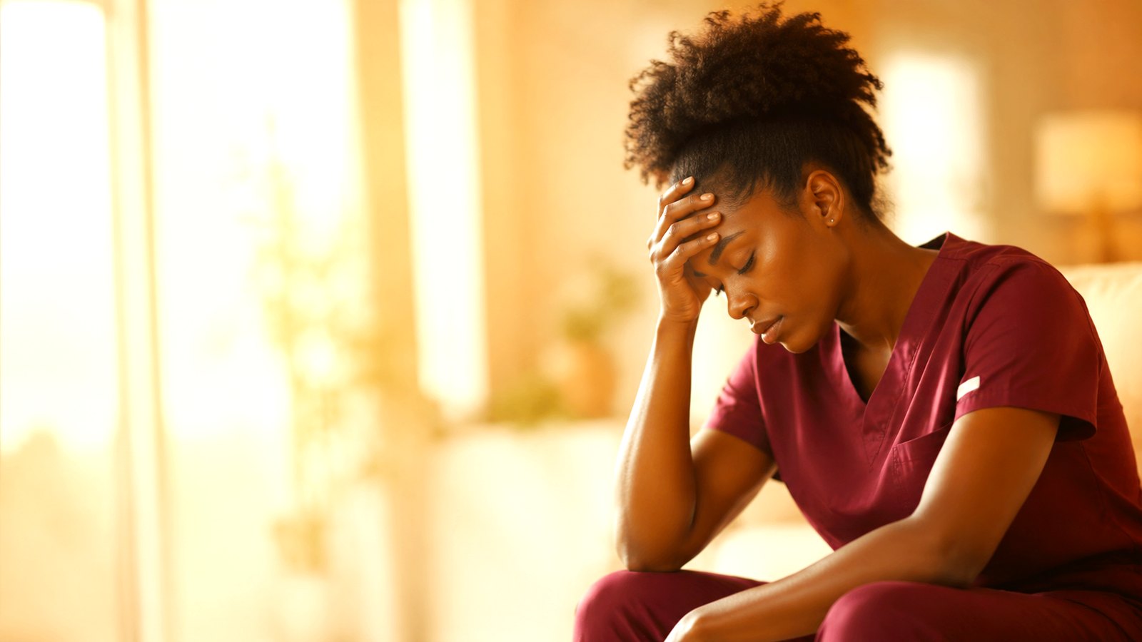 A weary behavioral-health caregiver resting in a sunlit room